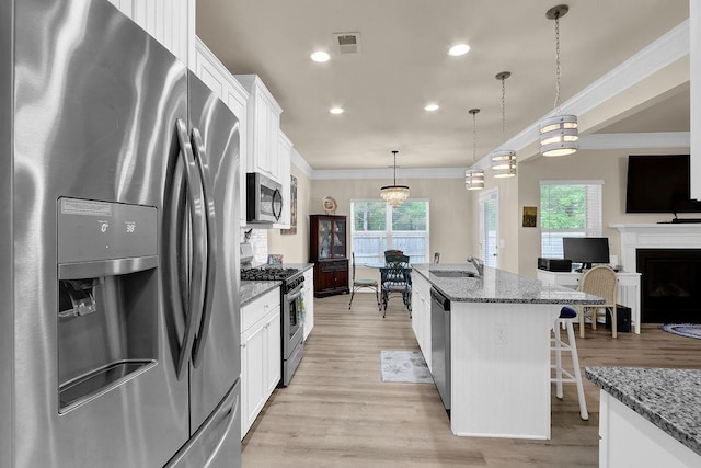 kitchen with appliances with stainless steel finishes, a sink, plenty of natural light, a breakfast bar area, and crown molding