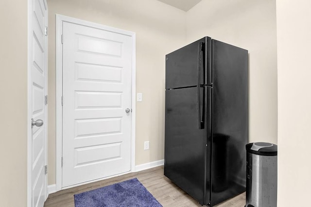 kitchen featuring freestanding refrigerator, wood finished floors, and baseboards
