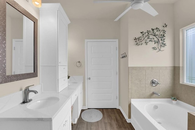 bathroom featuring wood finished floors, a ceiling fan, a bath, and double vanity