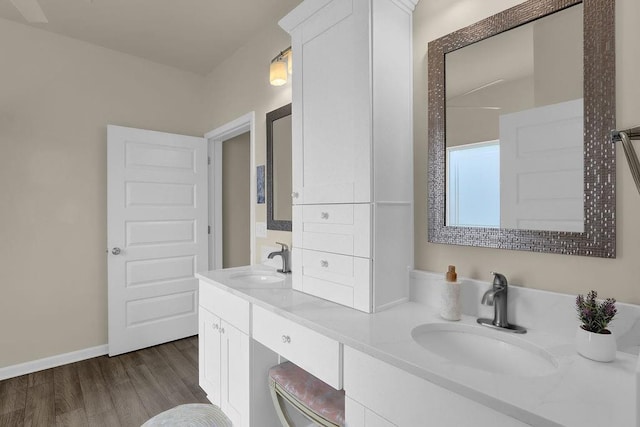 full bathroom with wood finished floors, double vanity, and baseboards