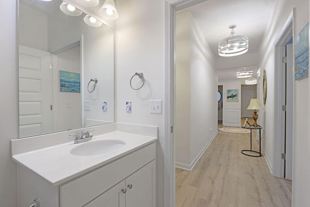 bathroom featuring wood finished floors, a chandelier, vanity, and baseboards