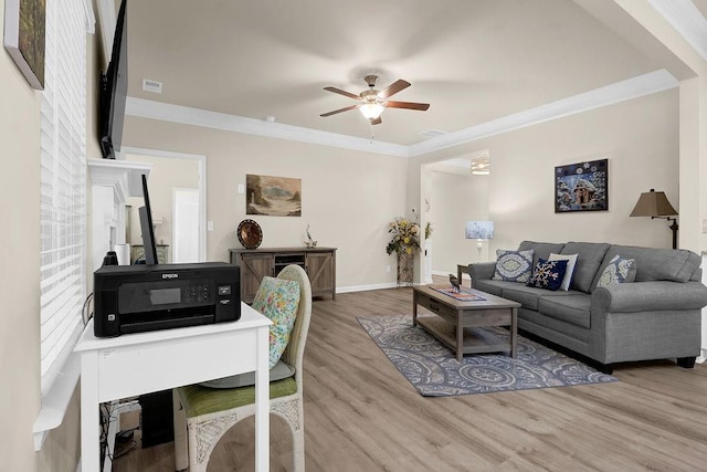 living room featuring wood finished floors, crown molding, a ceiling fan, and baseboards