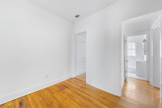 unfurnished room with light wood-type flooring, visible vents, and baseboards