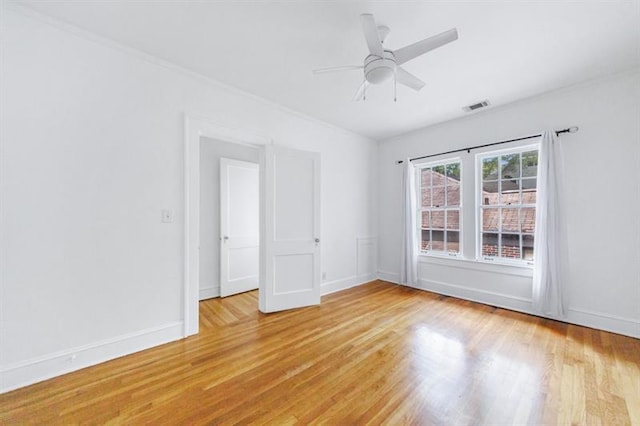 unfurnished room with a ceiling fan, visible vents, baseboards, and wood finished floors