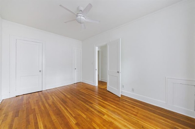 spare room with wood finished floors, a ceiling fan, and baseboards