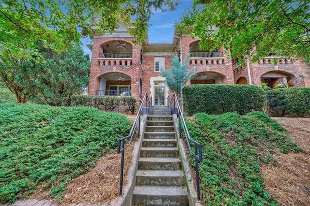 view of front of house featuring stairway and brick siding