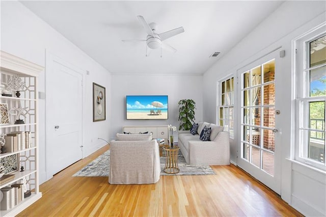 living room with a ceiling fan, visible vents, and wood finished floors