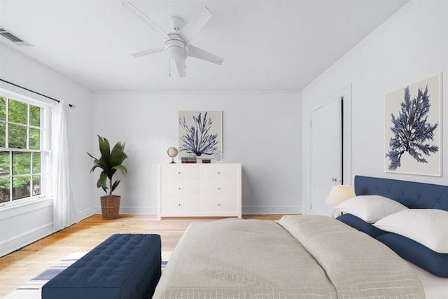 bedroom featuring baseboards, visible vents, ceiling fan, and wood finished floors