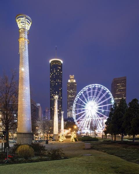 view of home's community with a view of city lights and a yard