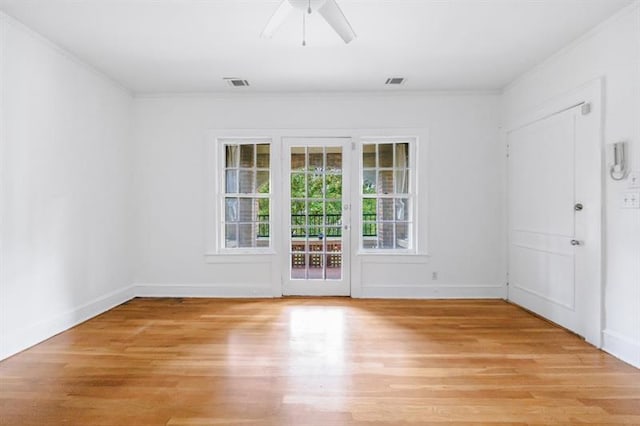 empty room with ornamental molding, visible vents, light wood finished floors, and a ceiling fan