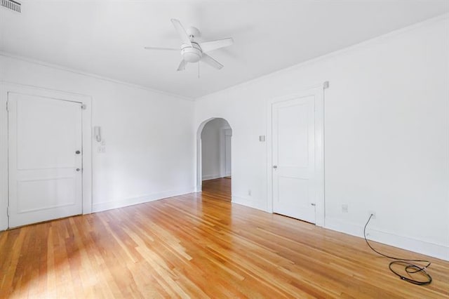 spare room featuring visible vents, arched walkways, baseboards, ceiling fan, and light wood-type flooring