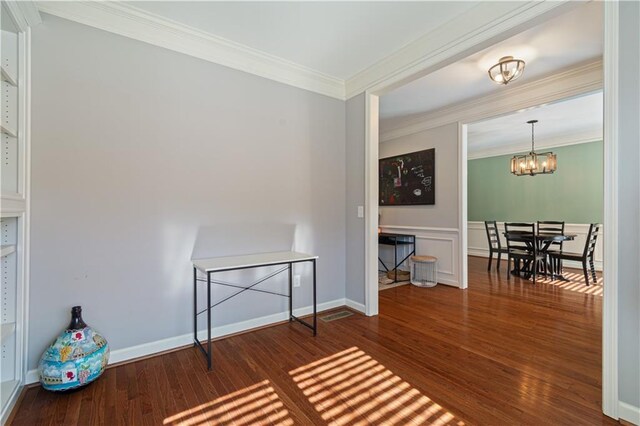 sitting room with dark wood-type flooring, crown molding, and a notable chandelier