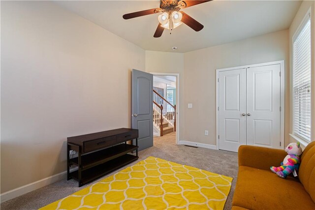 living area with ceiling fan, a healthy amount of sunlight, and light carpet