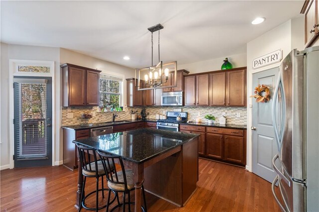 kitchen featuring dark hardwood / wood-style flooring, a center island, pendant lighting, and appliances with stainless steel finishes