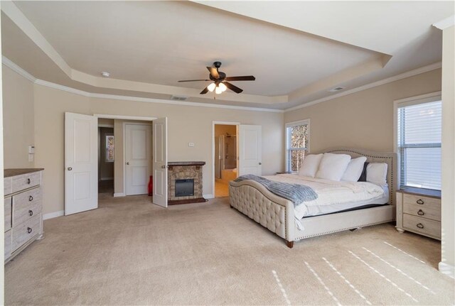 bedroom with a raised ceiling, multiple windows, ceiling fan, and light carpet