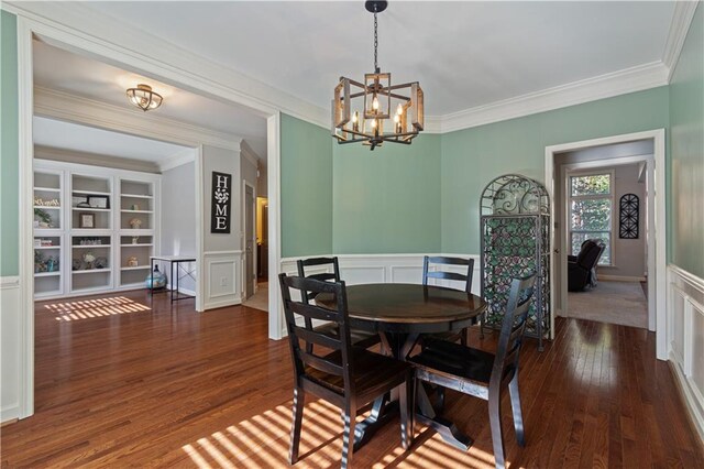 dining space featuring ornamental molding, dark wood-type flooring, and an inviting chandelier