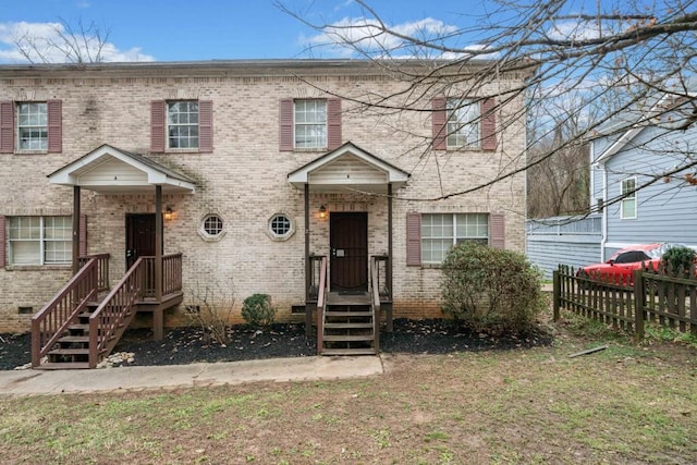 view of property with fence, brick siding, and crawl space