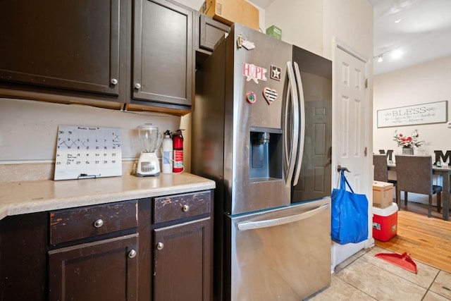 kitchen featuring dark brown cabinets, light tile patterned flooring, stainless steel refrigerator with ice dispenser, and light countertops