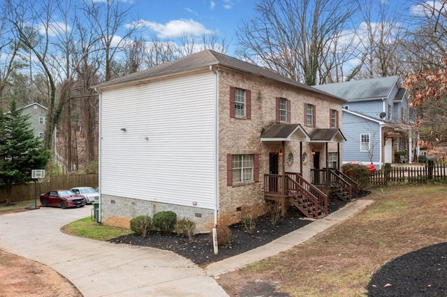 view of front of property featuring crawl space, brick siding, driveway, and fence