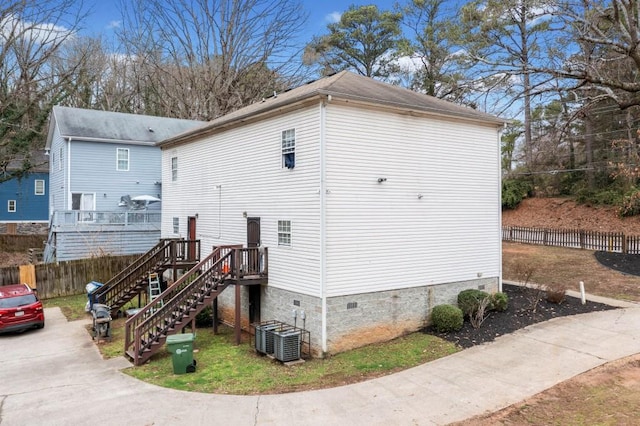 view of side of property with central air condition unit, stairway, fence, and crawl space