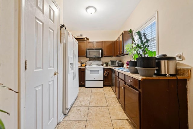 kitchen featuring light tile patterned floors, a toaster, white appliances, and light countertops