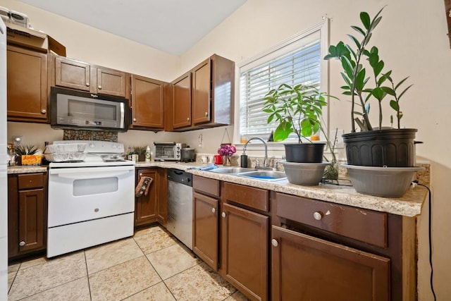 kitchen with light countertops, light tile patterned floors, appliances with stainless steel finishes, and a sink