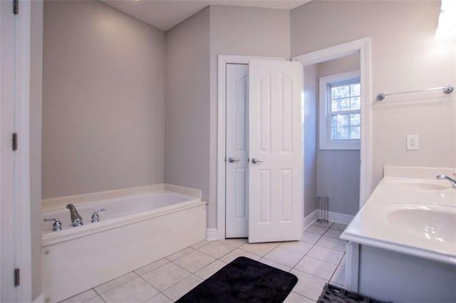 bathroom featuring tile patterned flooring, baseboards, a garden tub, double vanity, and a sink