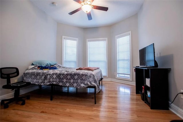 bedroom featuring light wood-style flooring, a ceiling fan, and baseboards