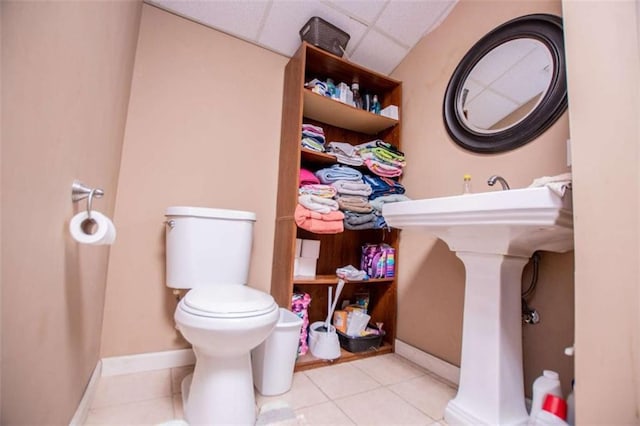 bathroom with tile patterned floors, baseboards, a paneled ceiling, and toilet