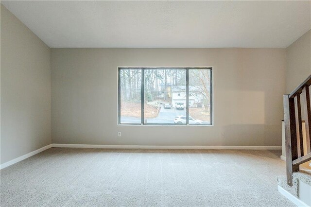 spare room featuring stairs, carpet floors, and baseboards