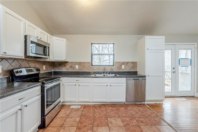 kitchen featuring french doors, backsplash, appliances with stainless steel finishes, white cabinets, and a sink