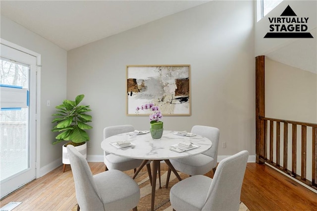 dining room with light wood-style floors, visible vents, baseboards, and vaulted ceiling