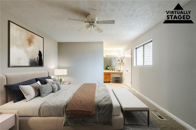 carpeted bedroom with visible vents, ensuite bathroom, ceiling fan, a textured ceiling, and baseboards