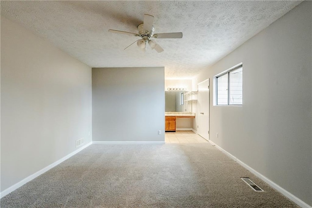 unfurnished room featuring a textured ceiling, light carpet, visible vents, baseboards, and built in study area