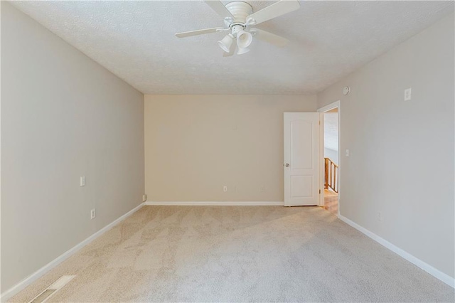 spare room featuring a ceiling fan, baseboards, a textured ceiling, and light colored carpet