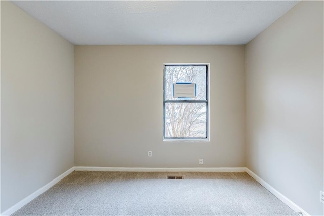 unfurnished room featuring carpet flooring, visible vents, and baseboards