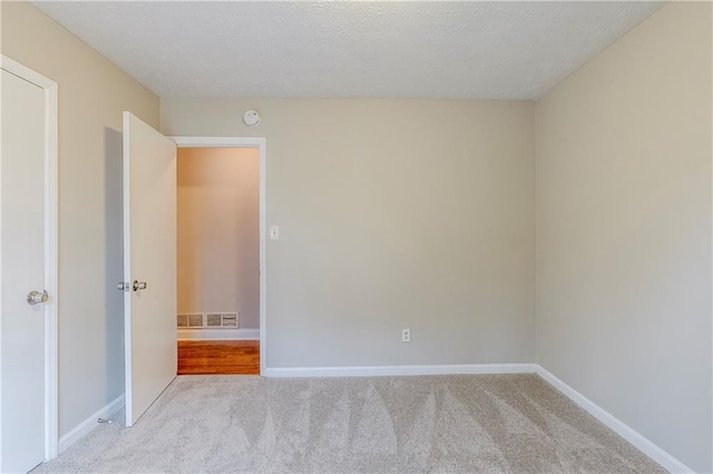 spare room featuring light carpet, baseboards, and visible vents