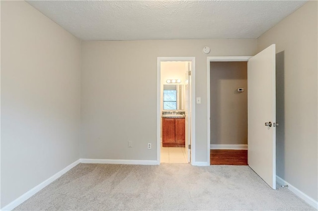 unfurnished bedroom with light carpet, baseboards, and a textured ceiling