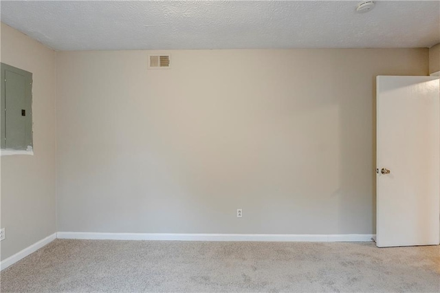 carpeted empty room featuring visible vents, a textured ceiling, electric panel, and baseboards