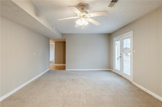 carpeted spare room with ceiling fan, a textured ceiling, visible vents, and baseboards