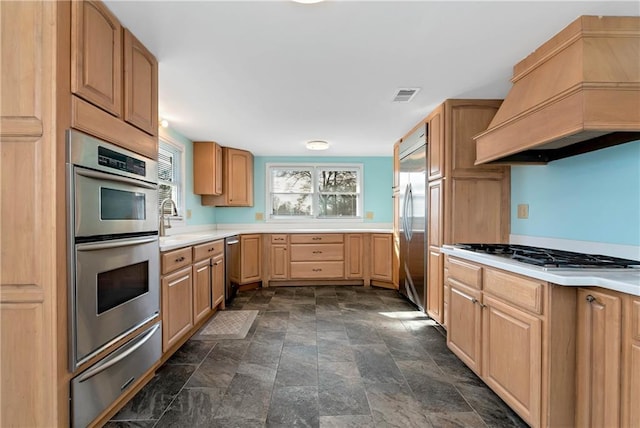 kitchen featuring appliances with stainless steel finishes, premium range hood, light brown cabinetry, and sink