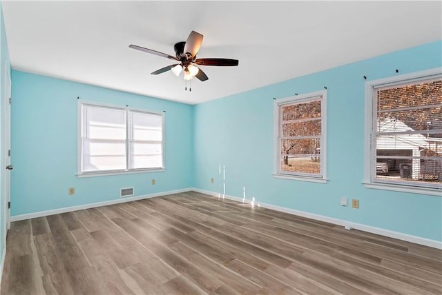 empty room with wood-type flooring, plenty of natural light, and ceiling fan