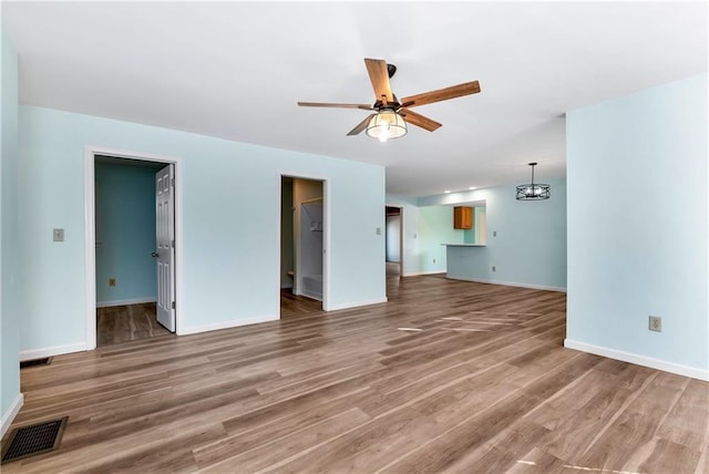 unfurnished living room featuring hardwood / wood-style flooring and ceiling fan with notable chandelier