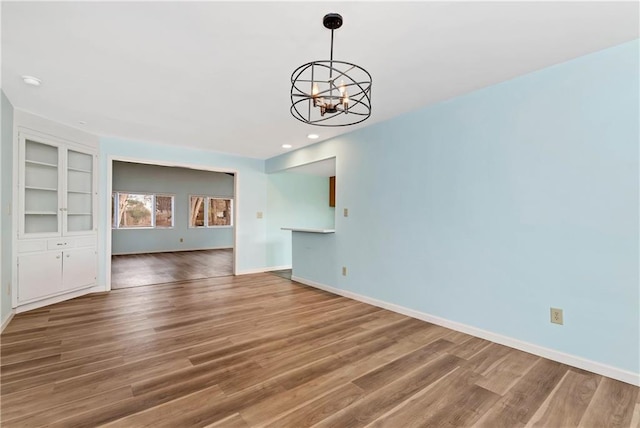 unfurnished living room featuring a chandelier, hardwood / wood-style floors, and built in features