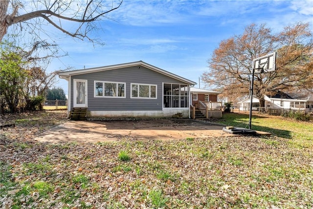 back of property featuring a lawn, a sunroom, and a patio