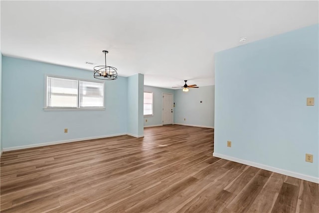 unfurnished living room with hardwood / wood-style floors and ceiling fan with notable chandelier