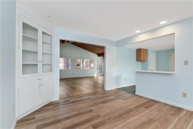 unfurnished living room featuring light hardwood / wood-style floors, lofted ceiling, and built in features