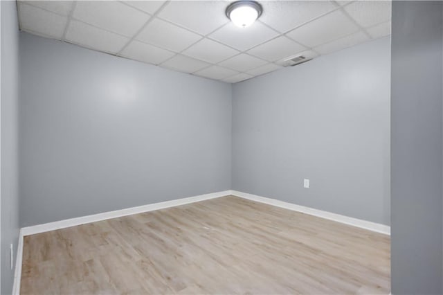 spare room featuring a drop ceiling and light hardwood / wood-style floors