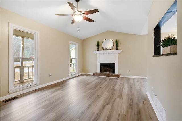 unfurnished living room with ceiling fan, vaulted ceiling, light hardwood / wood-style floors, and a healthy amount of sunlight