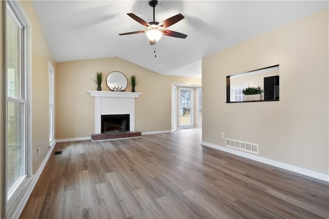 unfurnished living room with wood-type flooring, vaulted ceiling, ceiling fan, and a fireplace